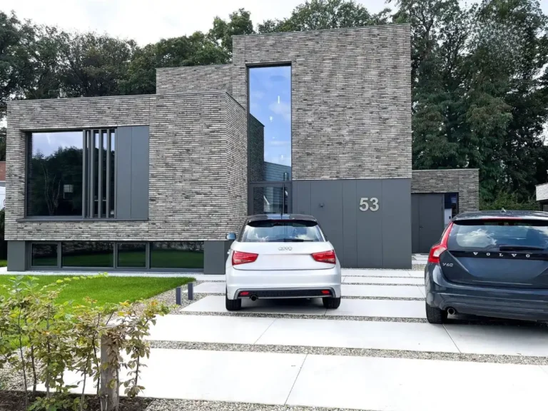 RVS huisnummer 53 in geborsteld staal op een grijze moderne gevel, strak gemonteerd bij een woning met luxe architectuur