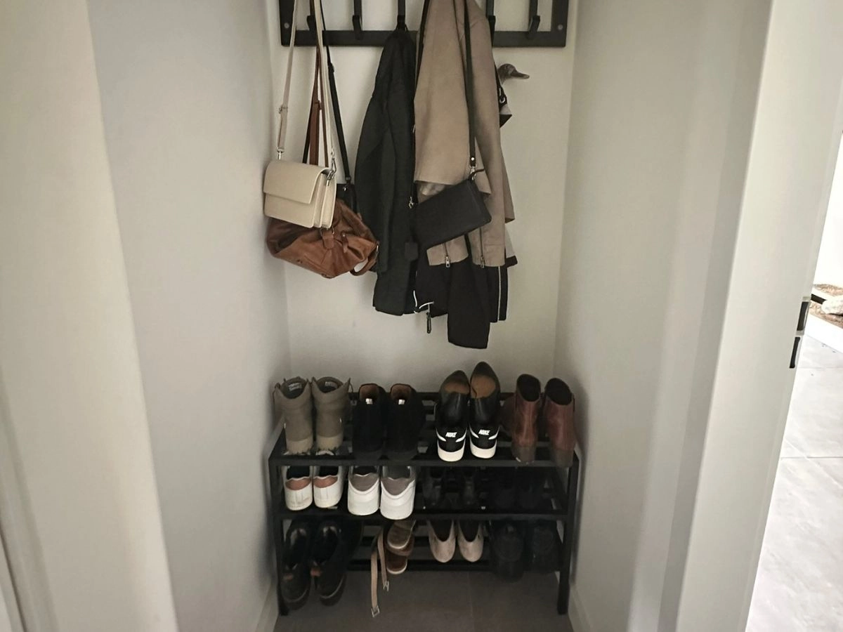 Op maat gemaakt RVS schoenenrek in nis onder een kapstok, gevuld met schoenen