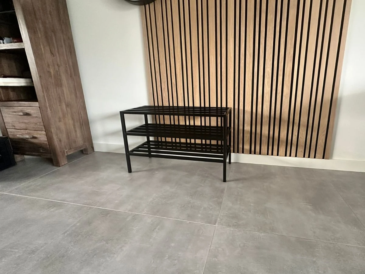 RVS schoenenrek met zwarte poedercoating, geplaatst voor een moderne houten lattenwand