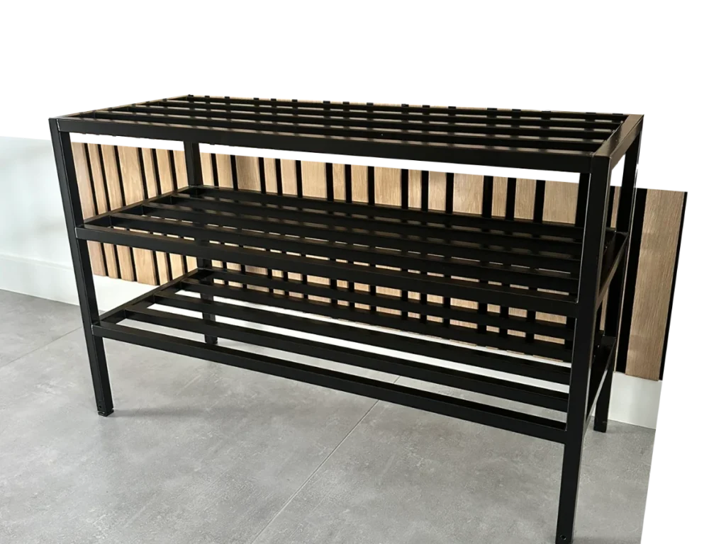 Zwart gepoedercoat RVS schoenenrek met drie etages in hoge uitvoering, geplaatst tegen een houten lattenwand